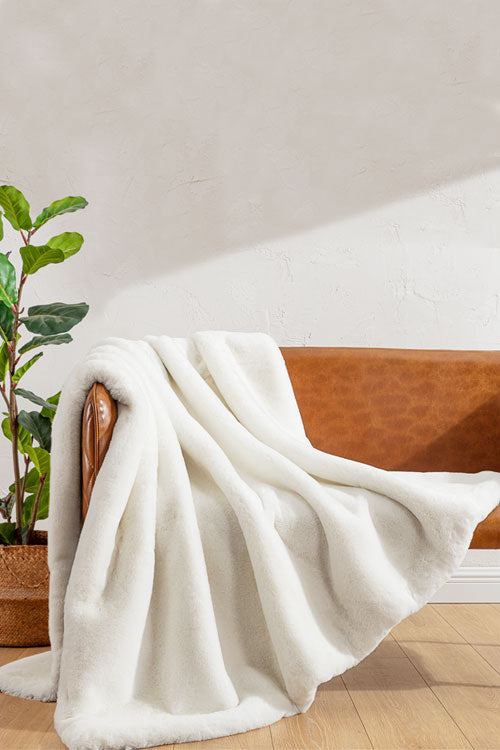 White faux fur blanket draped over a leather chair