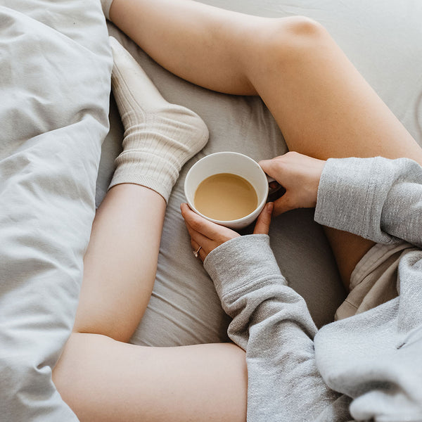 woman sitting on bed with a cup of coffee