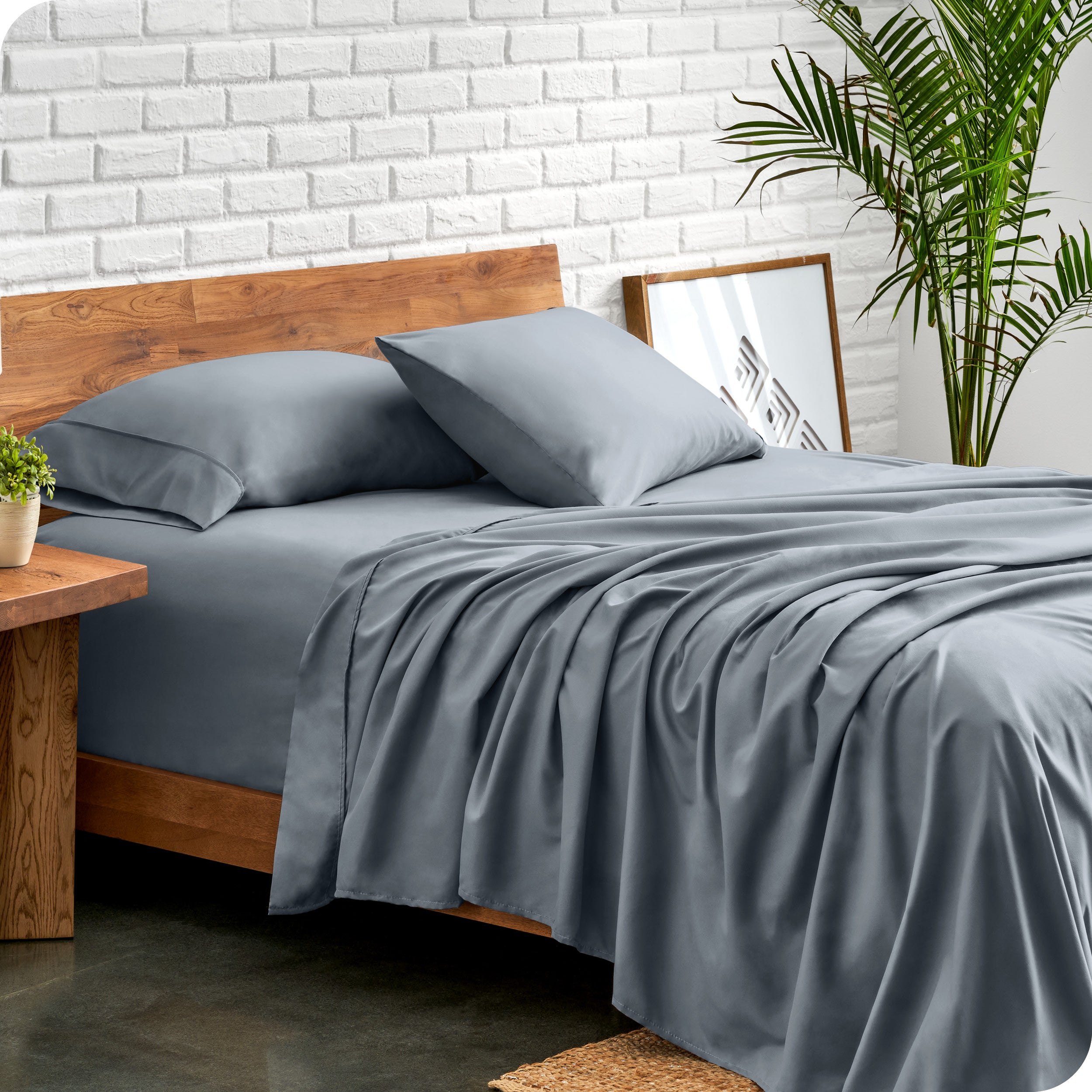 Bed with microfiber sheets against a white brick wall