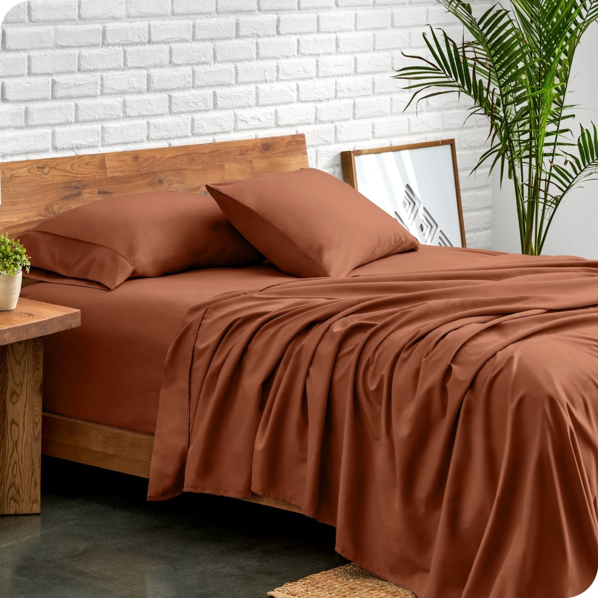 Bed with microfiber sheets against a white brick wall