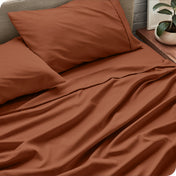 Sheet set on a bed with pillows and a plant in the background