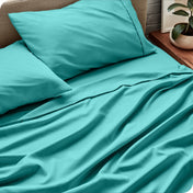 Sheet set on a bed with pillows and a plant in the background