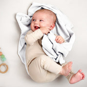 A baby lying on a receiving blanket. She has her thumb in her mouth.