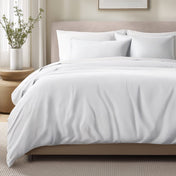 Bed with sateen bedding and pillows in a bedroom setting