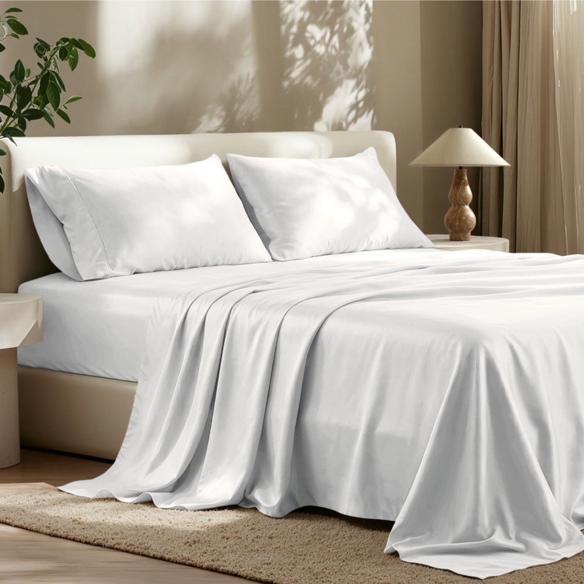 Sheet set on a bed in a bedroom with a lamp and plant.
