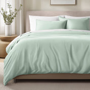 Bed with sateen bedding and pillows in a bedroom setting