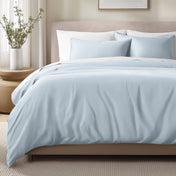 Bed with sateen bedding and pillows in a bedroom setting