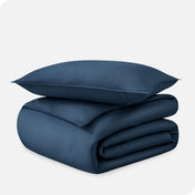 A folded organic sateen duvet cover with a pillow on top.