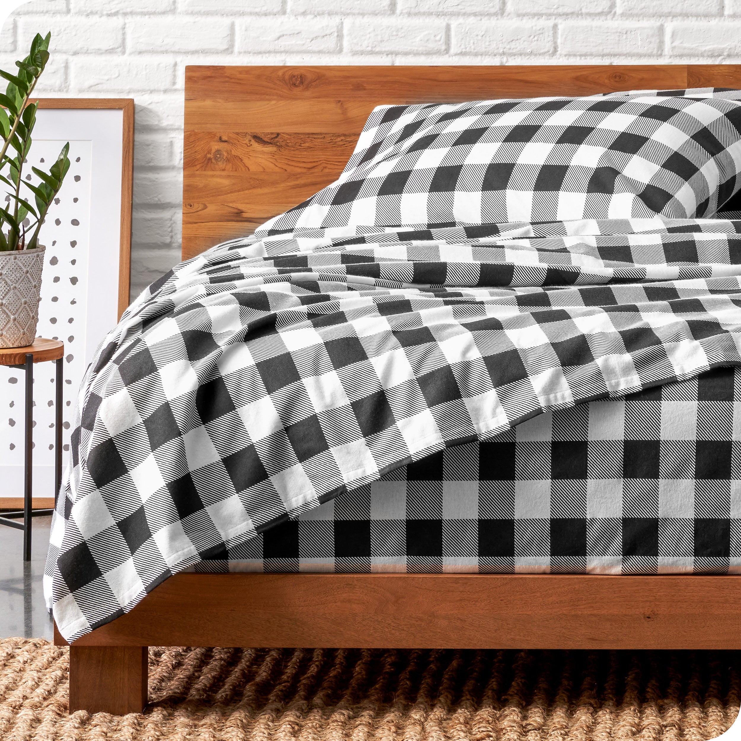Wooden bed frame with flannel print sheets on the bed
