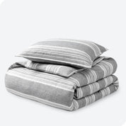 A stack of two pillows on top of a folded microfiber duvet cover.