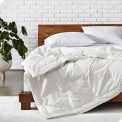 Bedroom showing modern wood bed with down filled comforter laying on the bed folded over on itself