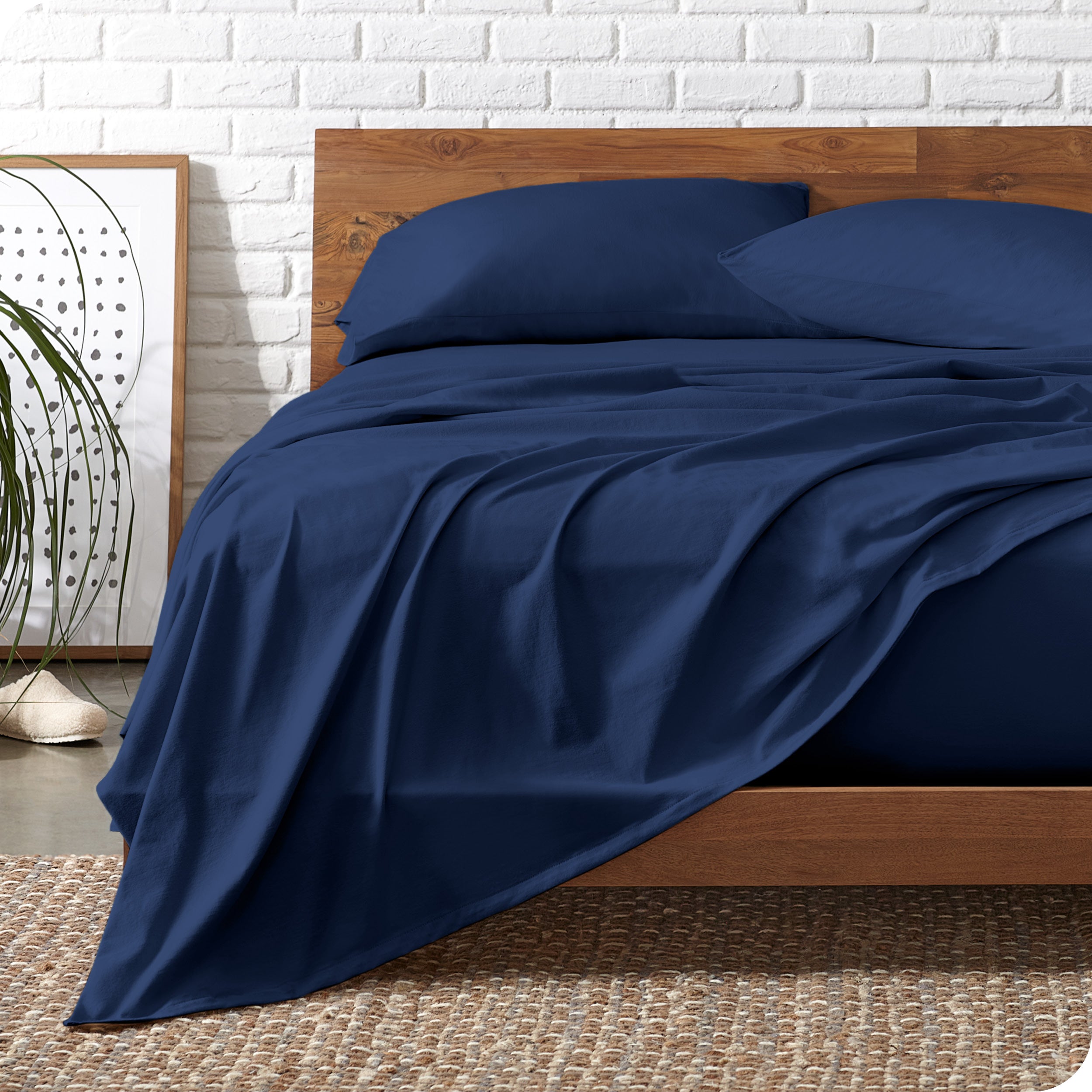 Wooden bed frame with dark blue organic cotton jersey sheets on the bed