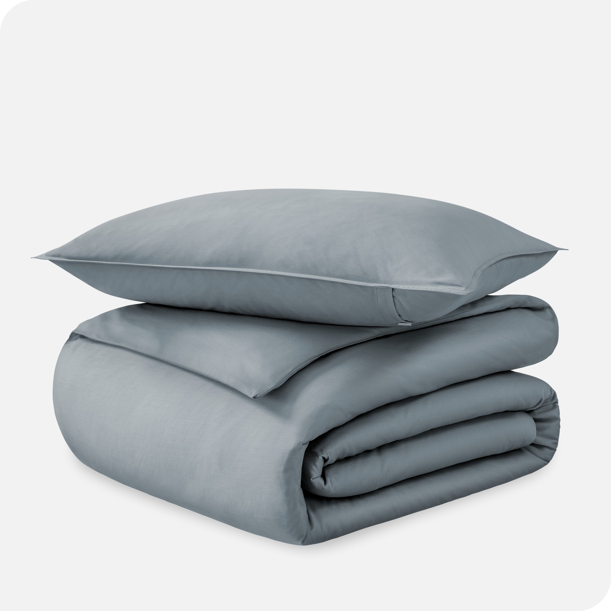 A folded organic sateen duvet cover with a pillow on top.