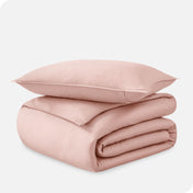 A folded organic sateen duvet cover with a pillow on top.