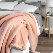 Faux fur blanket draped over the corner of a bed