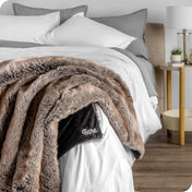 Faux fur blanket draped over the corner of a bed