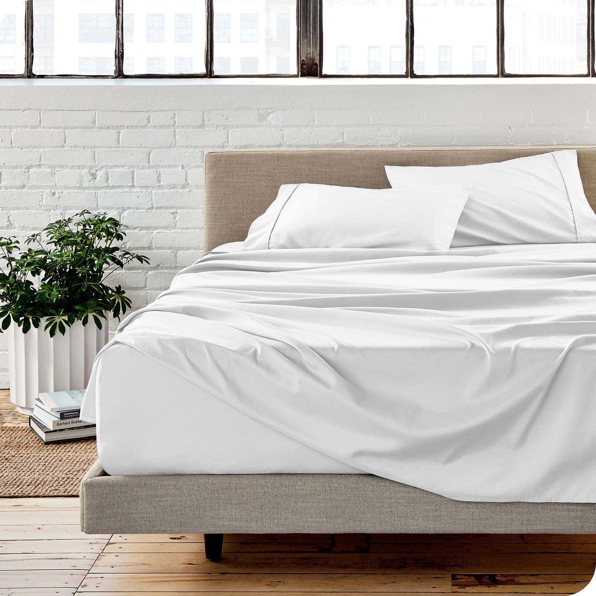 A modern bedroom with white sheets on the the bed with matching pillowcases