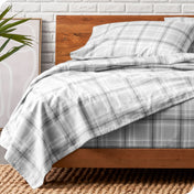 Wooden bed frame with flannel print sheets on the bed