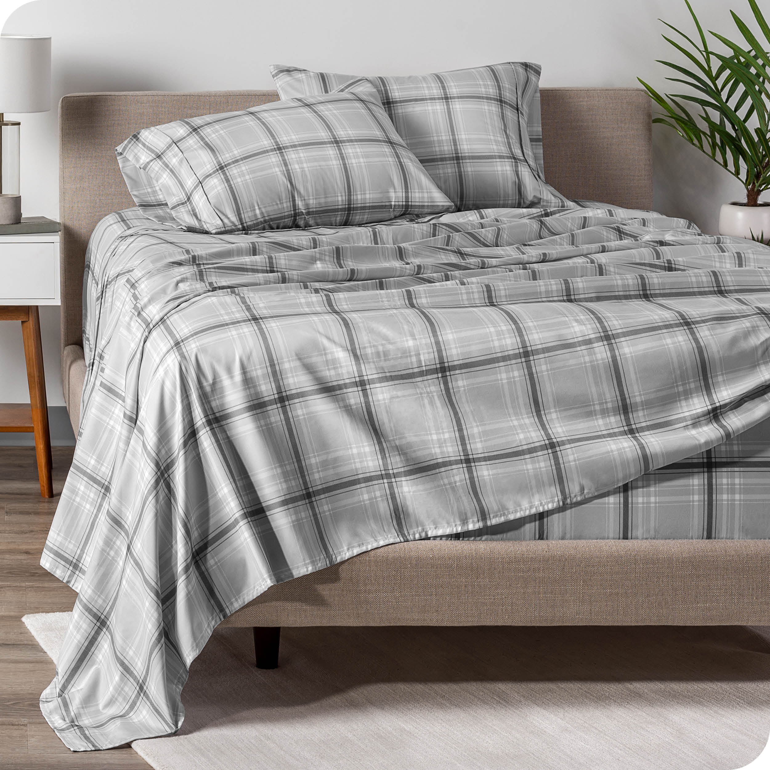 A modern bed with a plaid microfiber sheet set on.