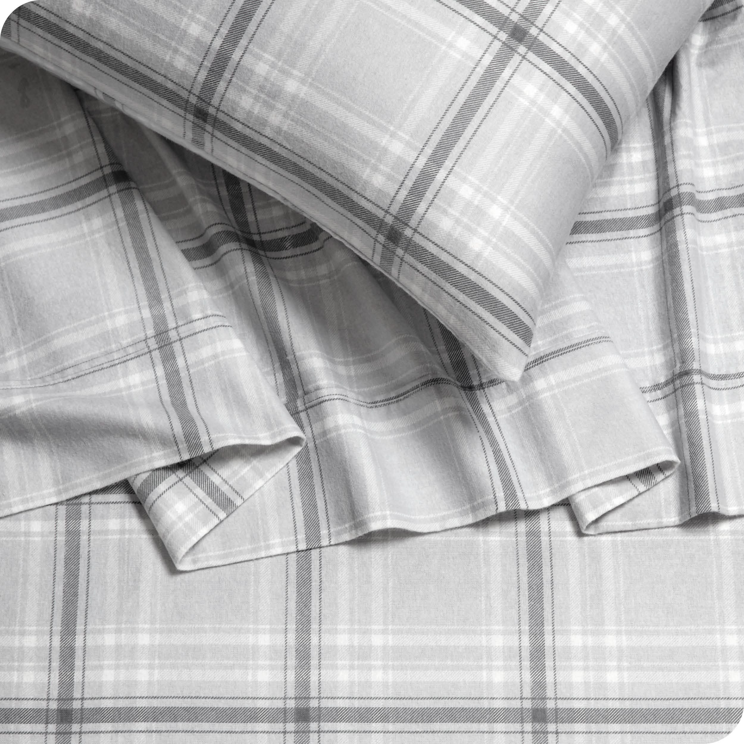 Close up of a pillowcase and sheets in grey plaid print