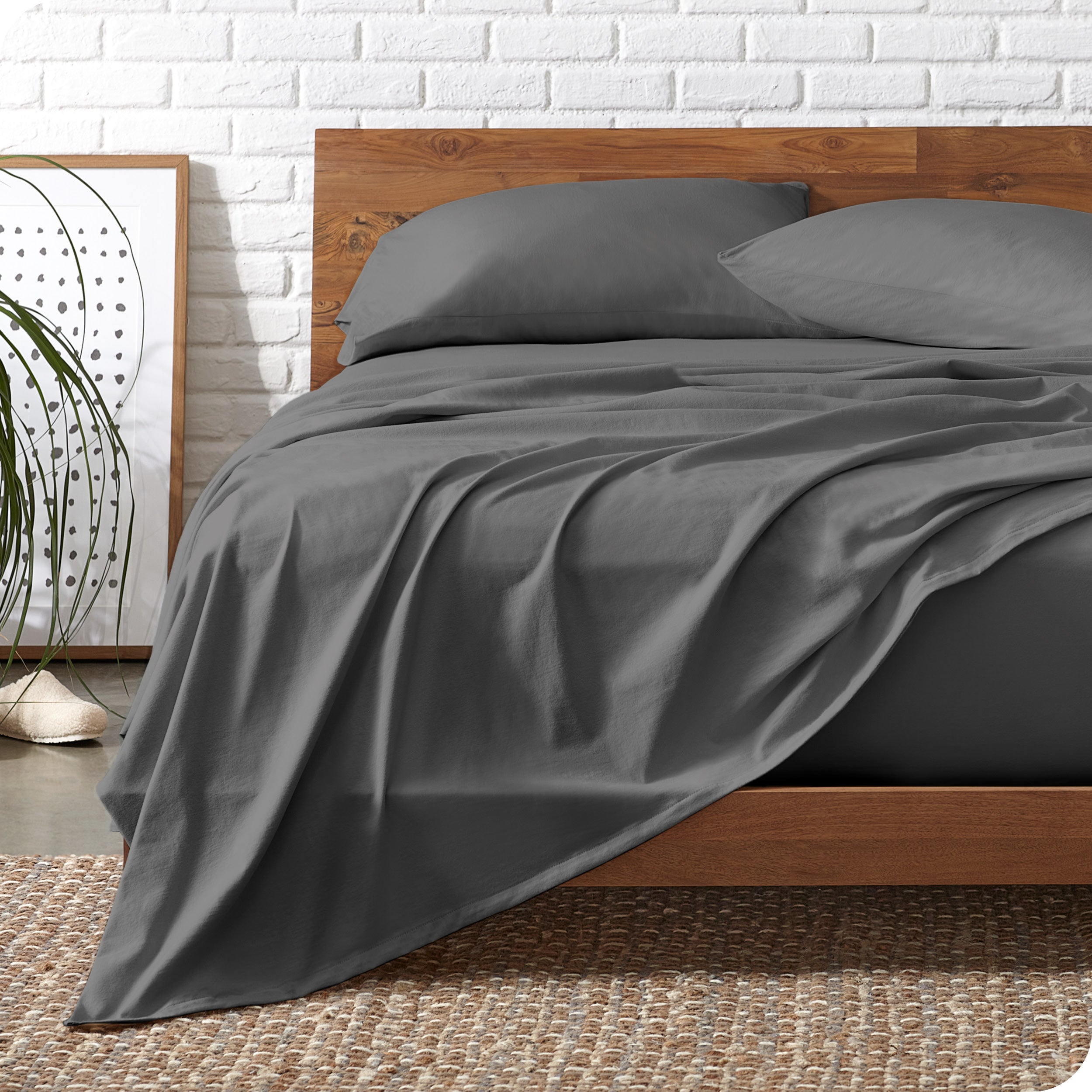 Wooden bed frame with grey organic cotton jersey sheets on the bed