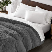 A modern bedroom with a shaggy duvet cover on the bed.