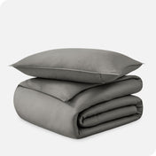 A folded organic sateen duvet cover with a pillow on top.