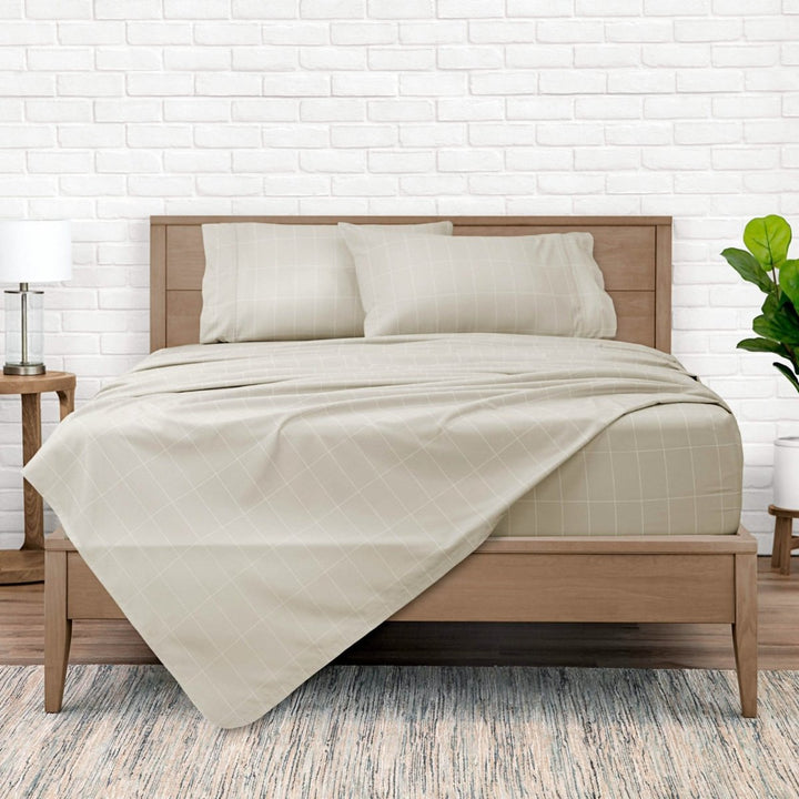 A modern bed with a printed grid pattern microfiber sheet set on the bed in color Stone White almost beige. The bed has a wooden bed frame and the sheet is on the bed in a diagonal manner.