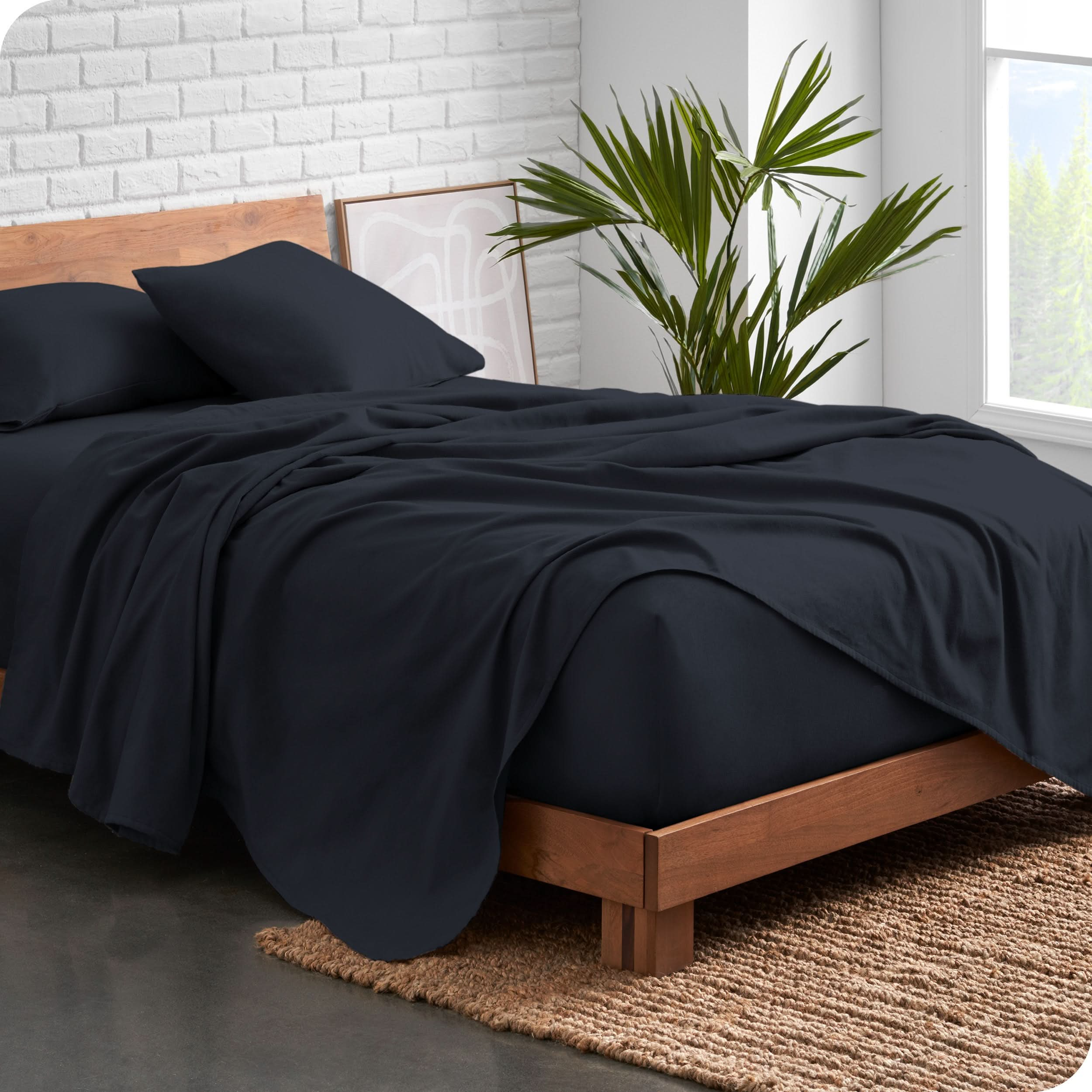 Modern wood bed frame with dark blue organic flannel sheets and pillowcases