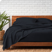 Modern wood bed frame with dark blue organic flannel sheets and pillowcases