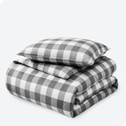 A stack of two pillows on top of a folded duvet with a white background.