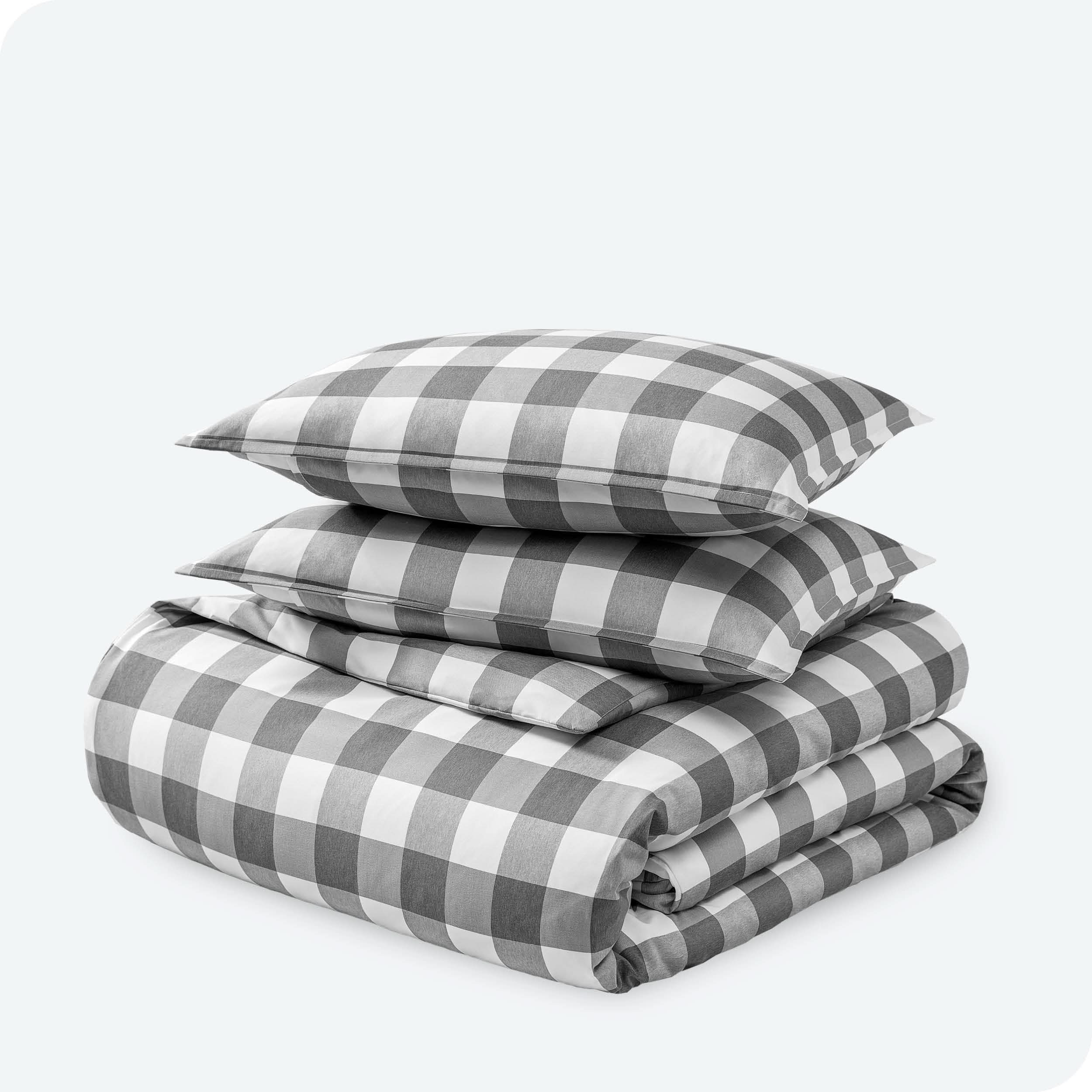 A stack of two pillows on top of a folded duvet with a white background.