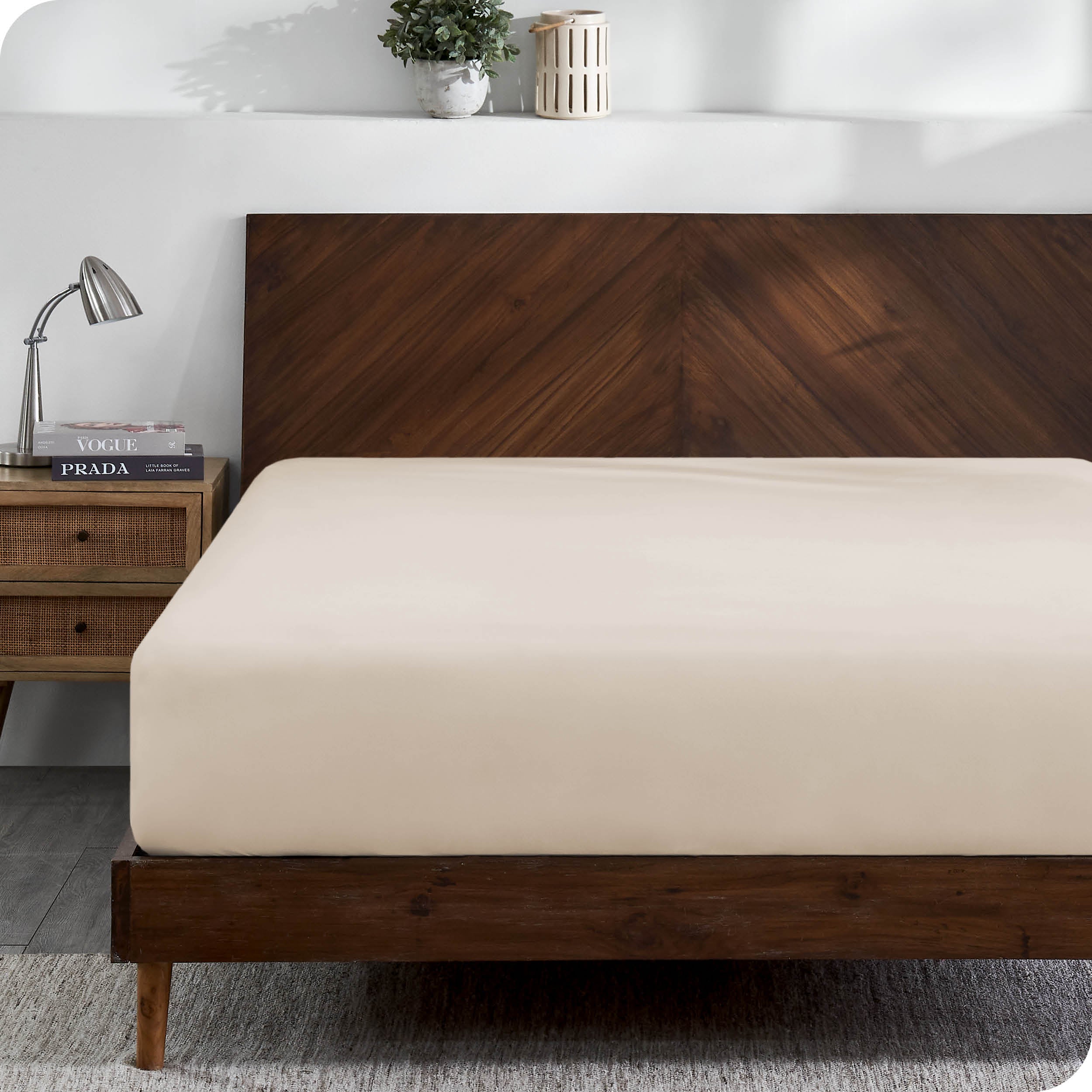 A modern wooden bed frame with a fitted sheet on the mattress
