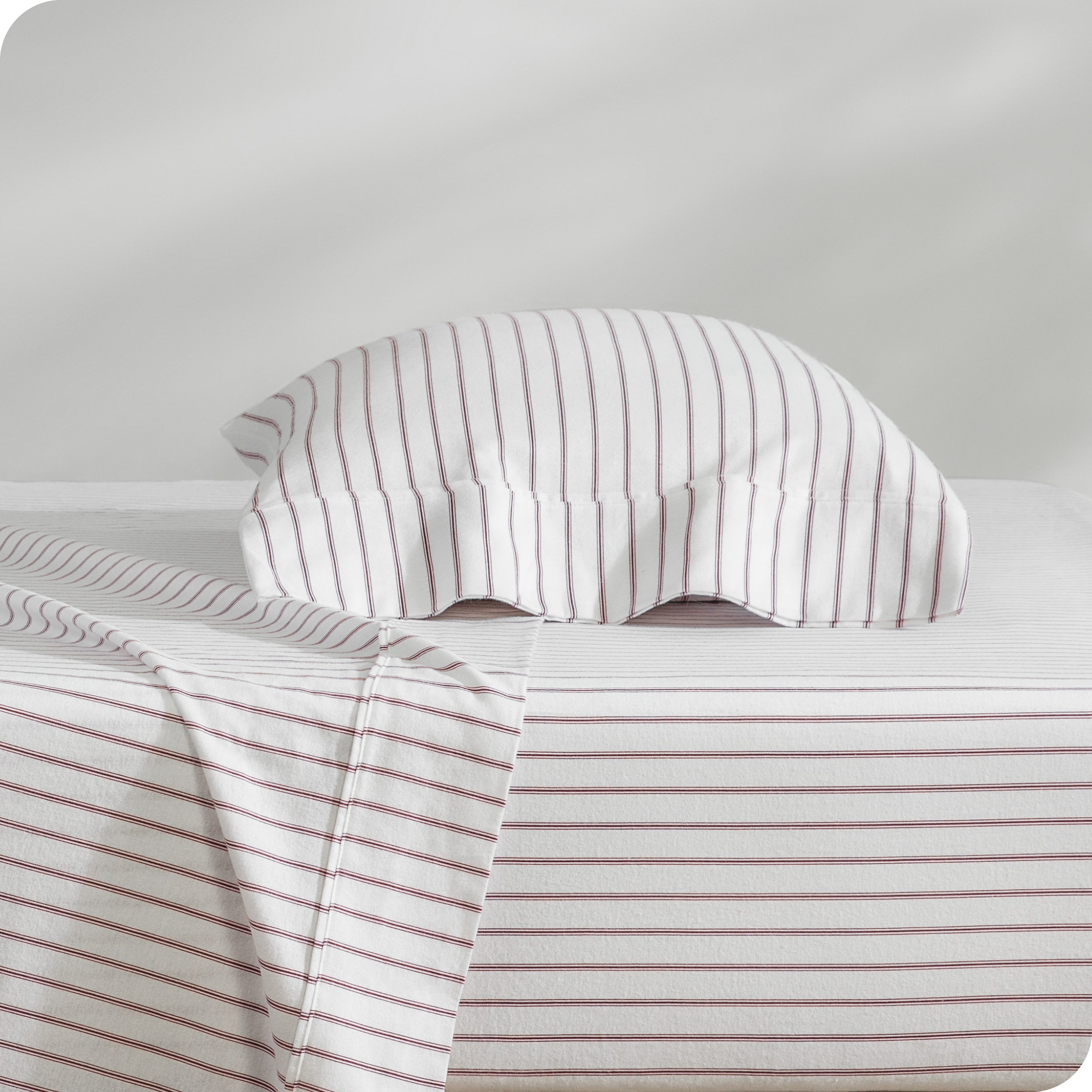 Flannel pillowcase with pillow inside stacked on a bed made with matching flannel sheets