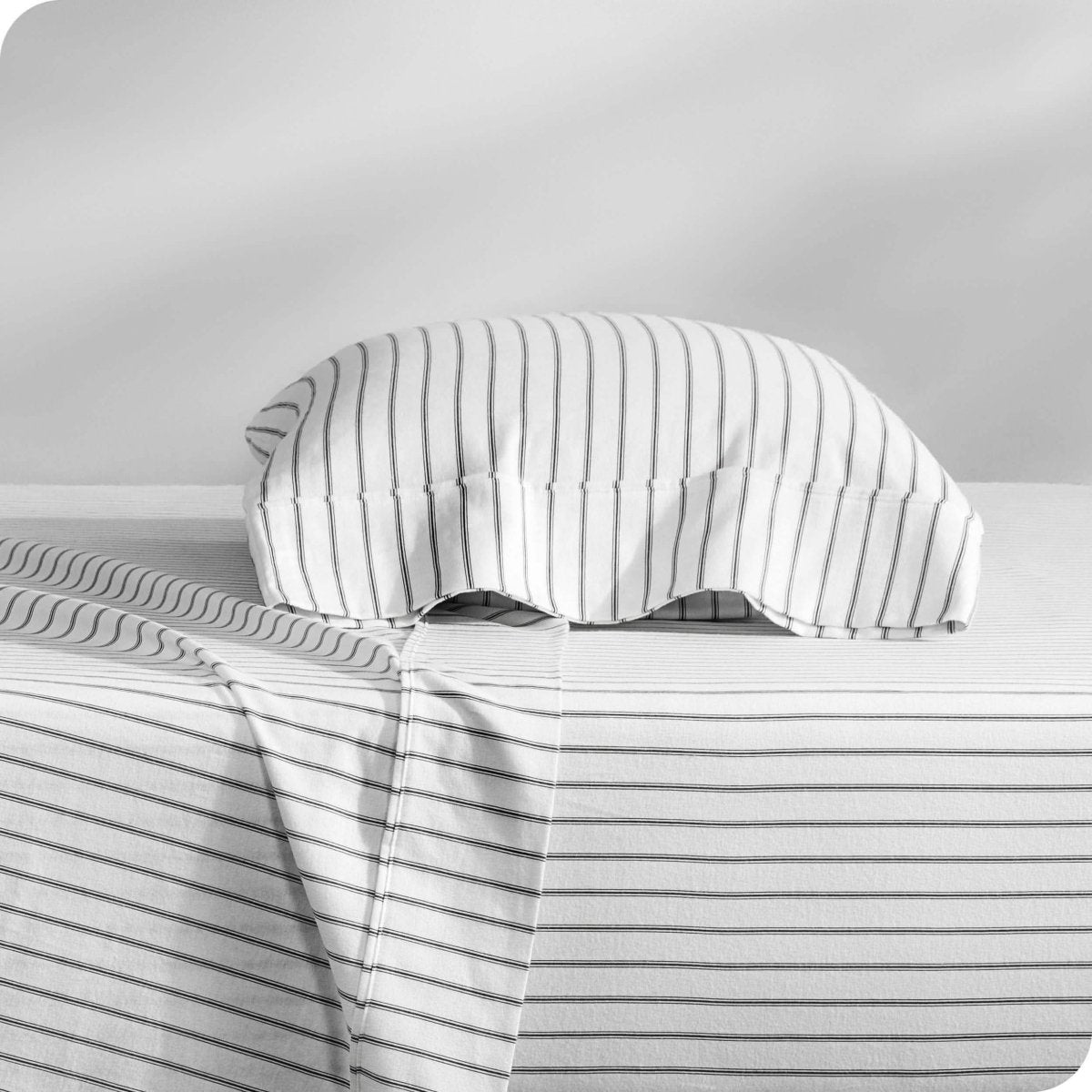 Flannel pillowcase with pillow inside stacked on a bed made with matching flannel sheets