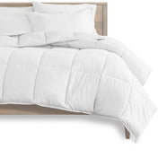 A modern bed with a white complete bedding set. The comforter is on the bed and the bedframe is a wooden frame. The background is white. There are a few white pillows on the bed.