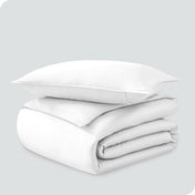 A folded organic sateen duvet cover with a pillow on top.