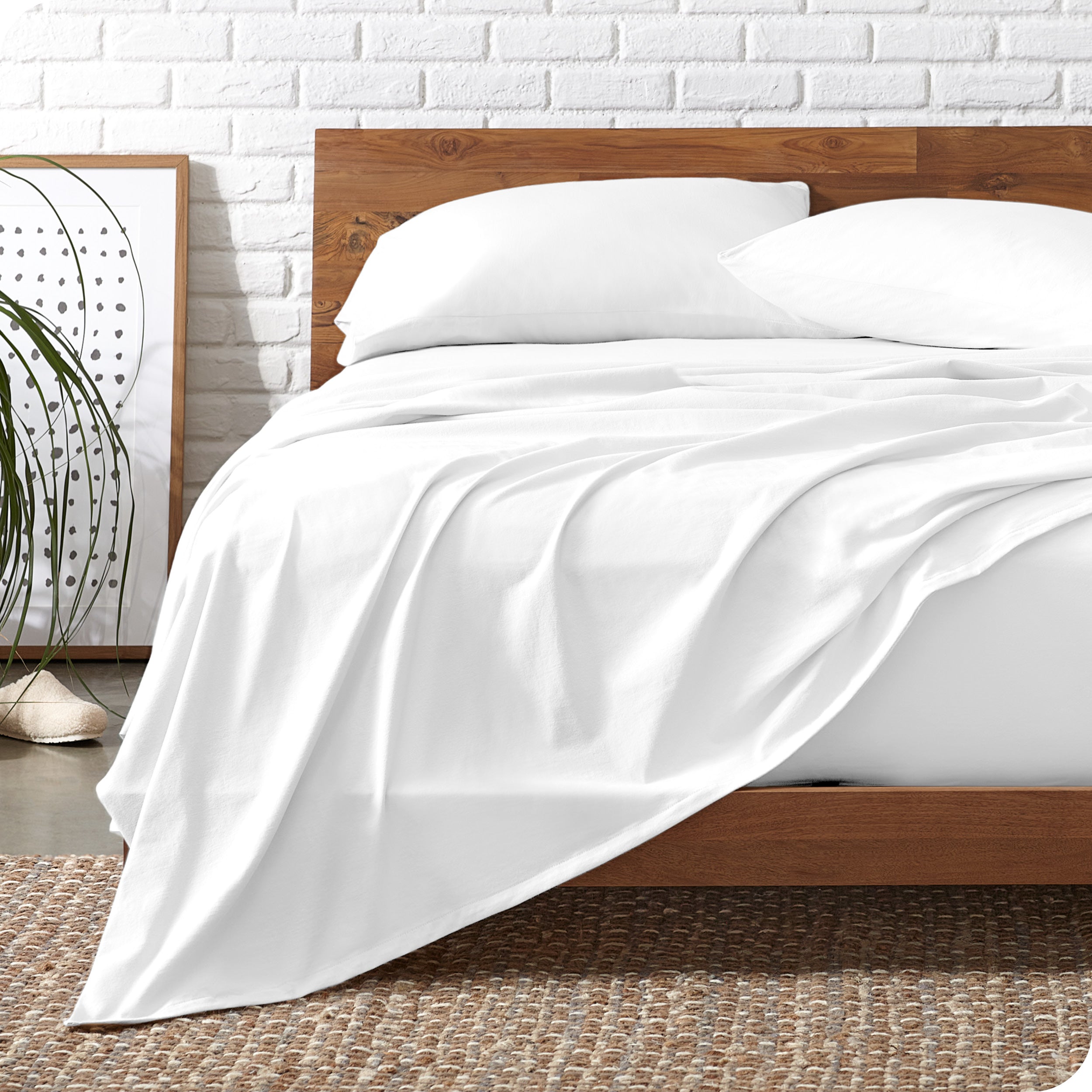 Wooden bed frame with white organic cotton jersey sheets on the bed