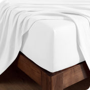 Close up of the corner of a mattress with a fitted sheet on it and a top sheet hanging over the side