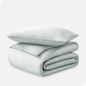 A folded organic sateen duvet cover with a pillow on top.