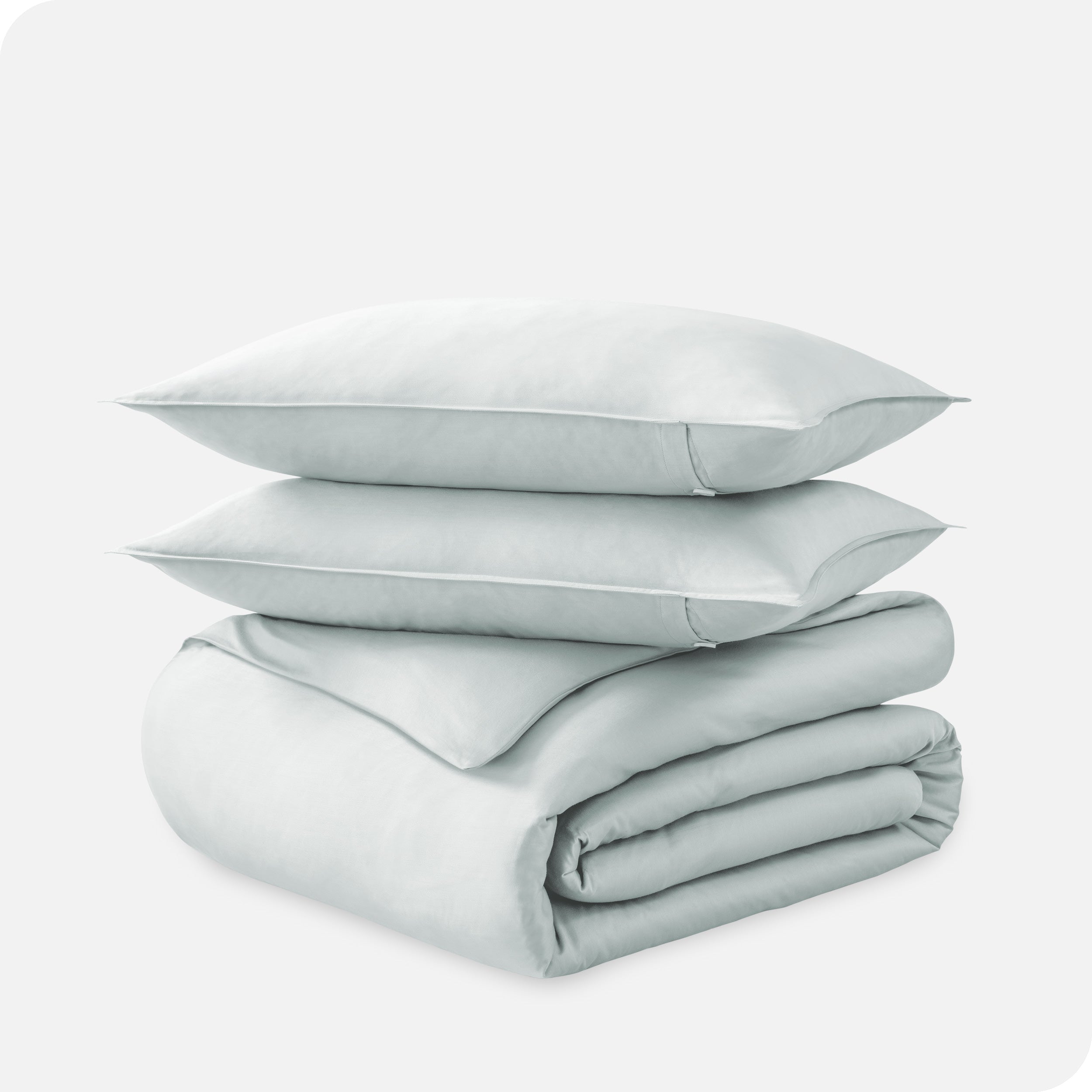 A folded organic sateen duvet cover with two pillows on top.