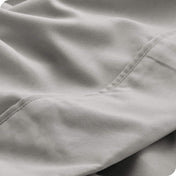 Close up of a light grey microfiber sheet showing the stitching and texture
