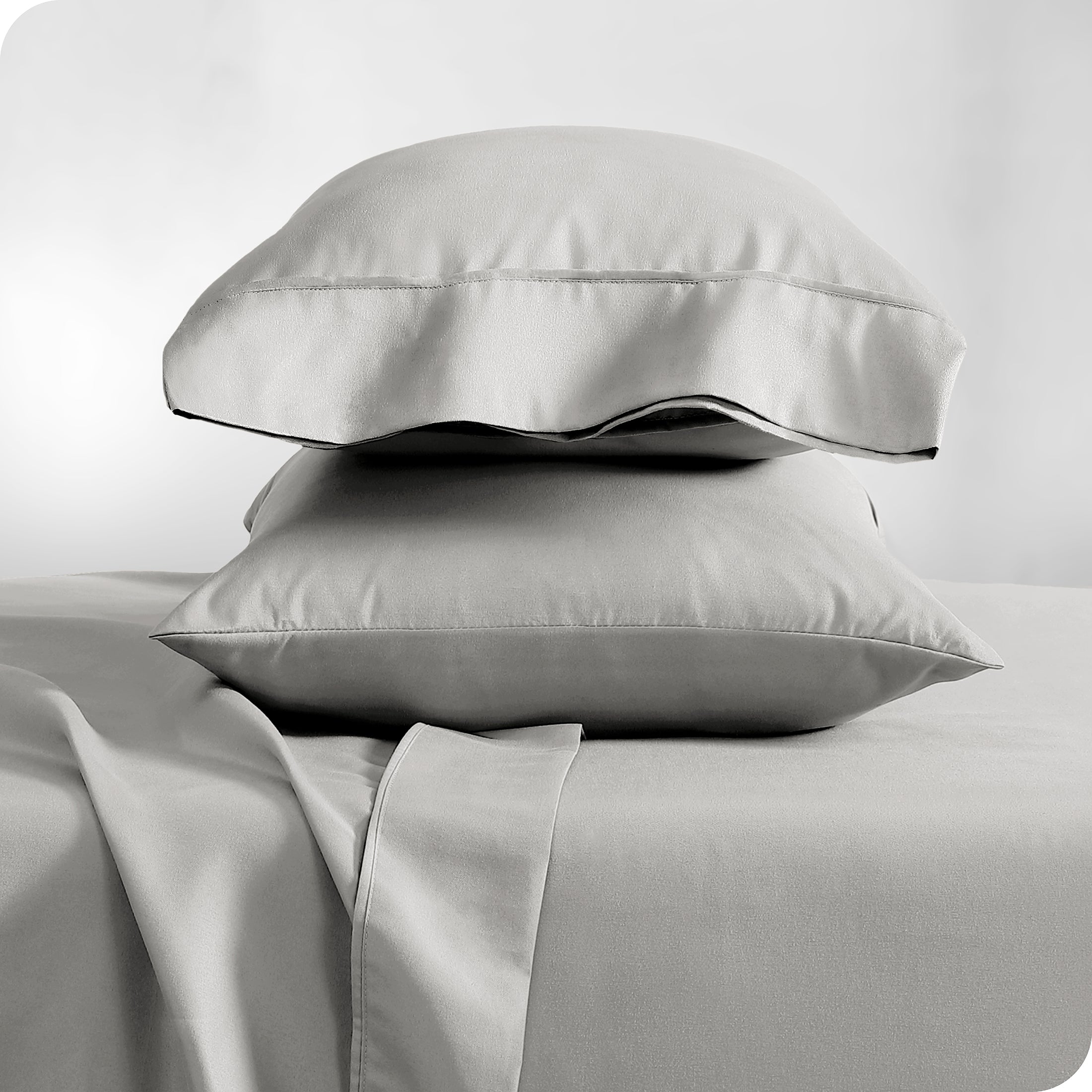 Two light grey pillowcases stacked on a bed