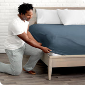 Man putting the corner of fitted sheet on a mattress