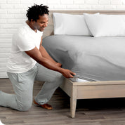 Man putting the corner of fitted sheet on a mattress