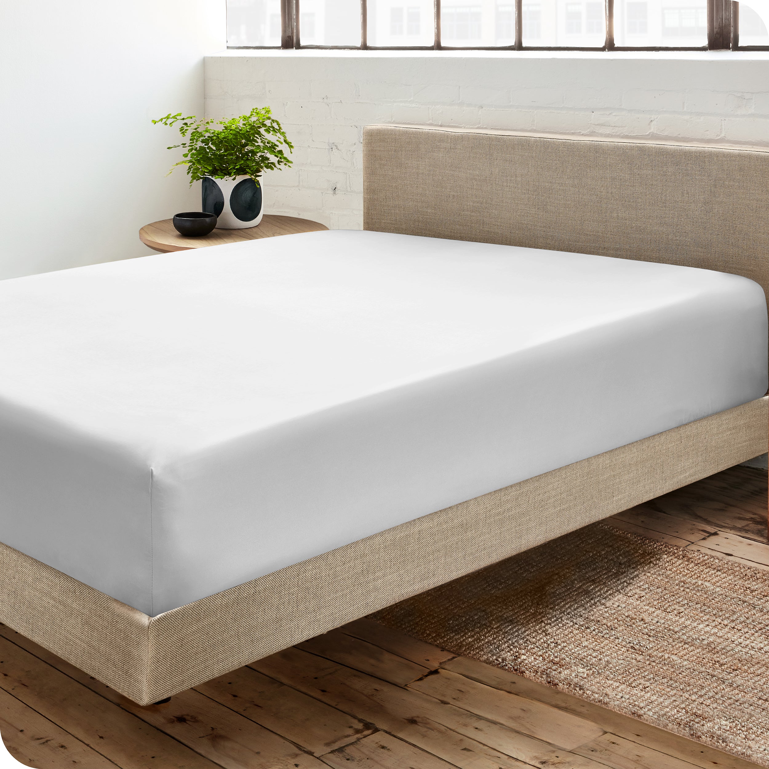 Diagonal view of modern bedroom with a white sateen fitted sheet on the bed