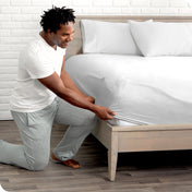 Man putting the corner of fitted sheet on a mattress