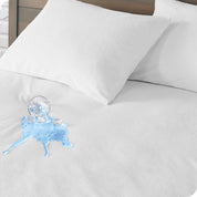 A glass of water spilled on a mattress protector. There are two pillows with protectors on the mattress.